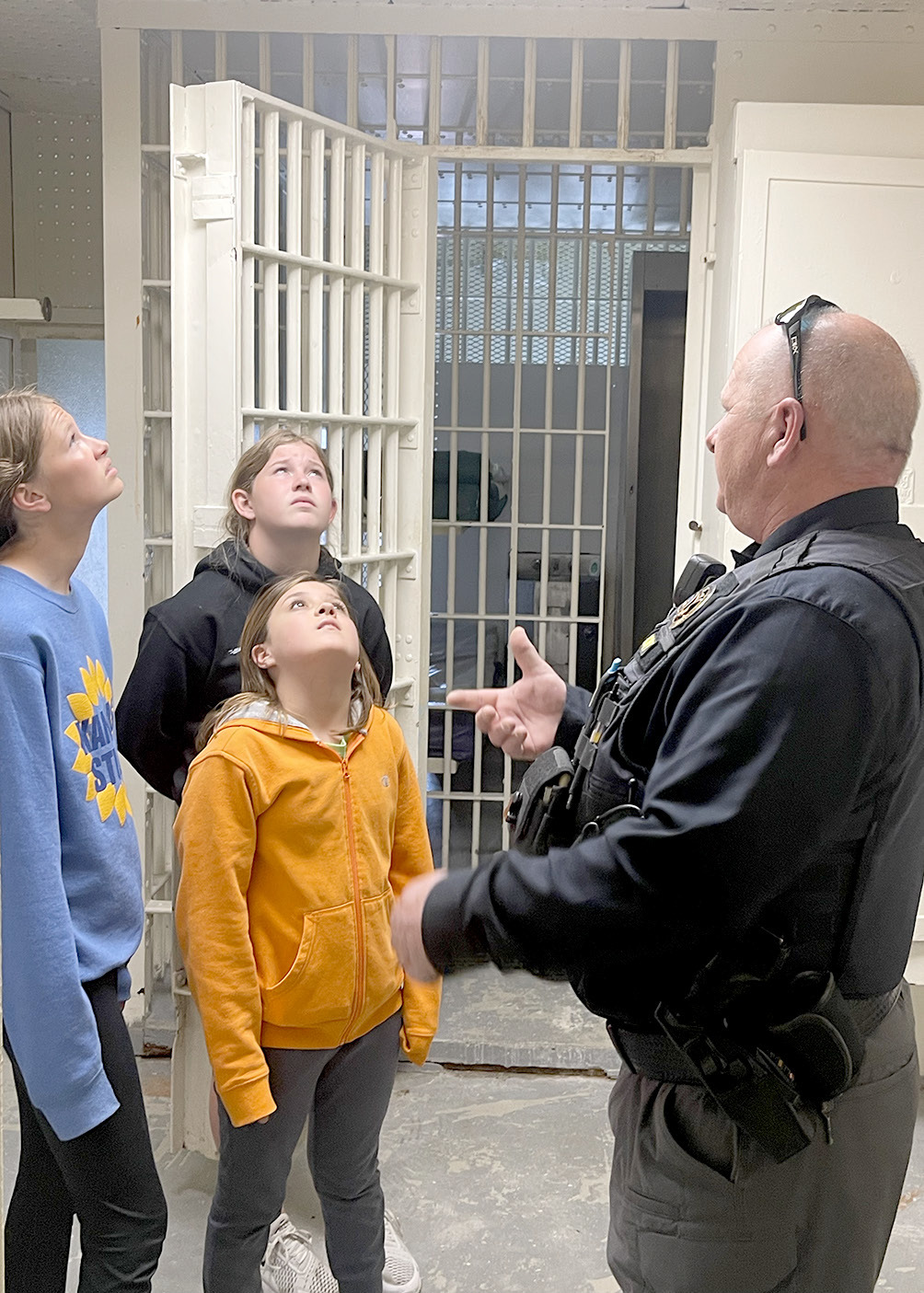 TEAGANN SHAMBURG, Jada Martin, and Serenity Carpenter listen to Lieutenant Collin Hockett talk about the Rooks County Jail, located on the fourth floor of the courthouse. It served the County for many decades, and was toured by many during the Centennial Celebration of the Rooks County Courthouse.