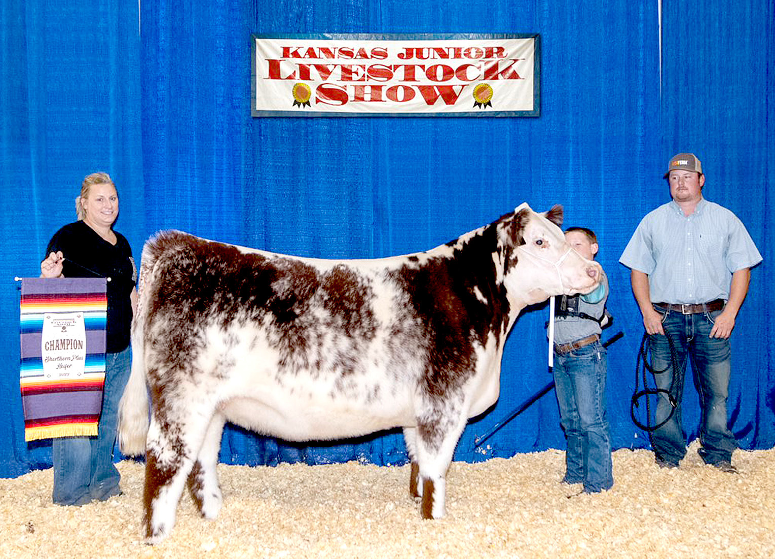 COLE FLOWER, in what was his first year competing at the Kansas Junior Livetock Show, brought home the Champion Shorthorn Heifer. Also shown with Cole are his proud parents, Courtney Hrabe, left, and Logan Flower, right.
