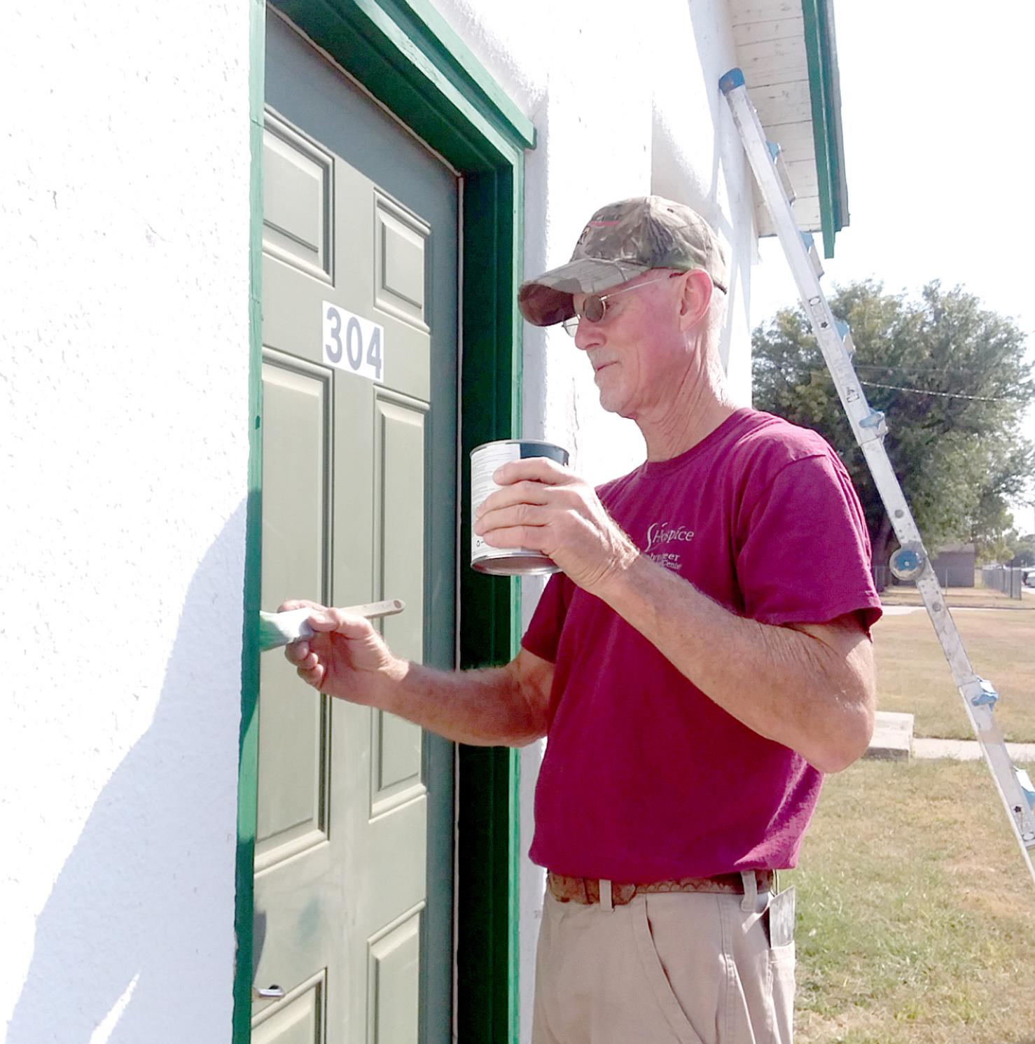 STOCKTON FOOD PANTRY DIRECTOR LARRY GOSSELIN paints the trim on the front door of the building. New windows have been installed, courtesy of donations from the public, and the paint and materials were donated by the City of Stockton.