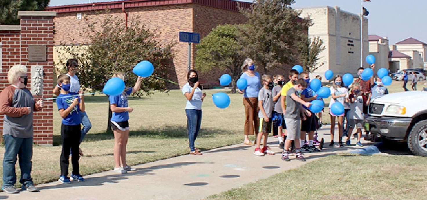 WITH BALLOONS RAISED, the fifth-grade class counts down and prepares to launch the balloons into the wind, with best wishes and prayers.