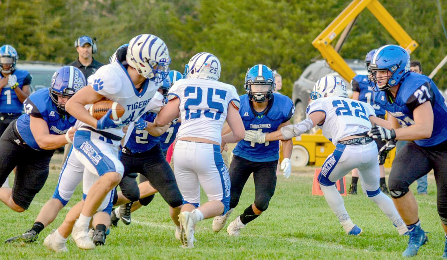 RYLAN BASART, with blockers Justus Hulse (#25) and Deyton Bedore (#22) leading the way, looks for a hole to run through Stockton’s game against Wheatland-Grinnell last Friday in Grinnell. The Tigers were defeated 54-22. (Photo courtesy of Brittany Lewis)