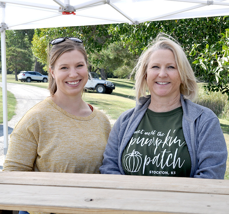 LYNDSEY BAUGHMAN (left) helped keep her mom, Lisa Gilmore, company while she was taking tickets at one of the entrances to the Pumpkin Patch last Saturday.