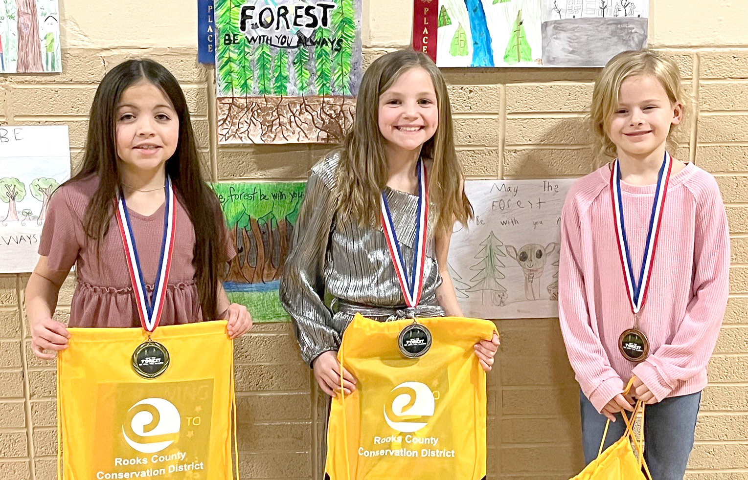 THIRD-GRADE POSTERWINNERS (l to r)—1st, LexiYounger, Plainville; 2nd, Norah Muir, Stockton; and 4th, Karly Dopita, Damar. Third-Place Winner Vanessa Parson, Sacred Heart, is not pictured.