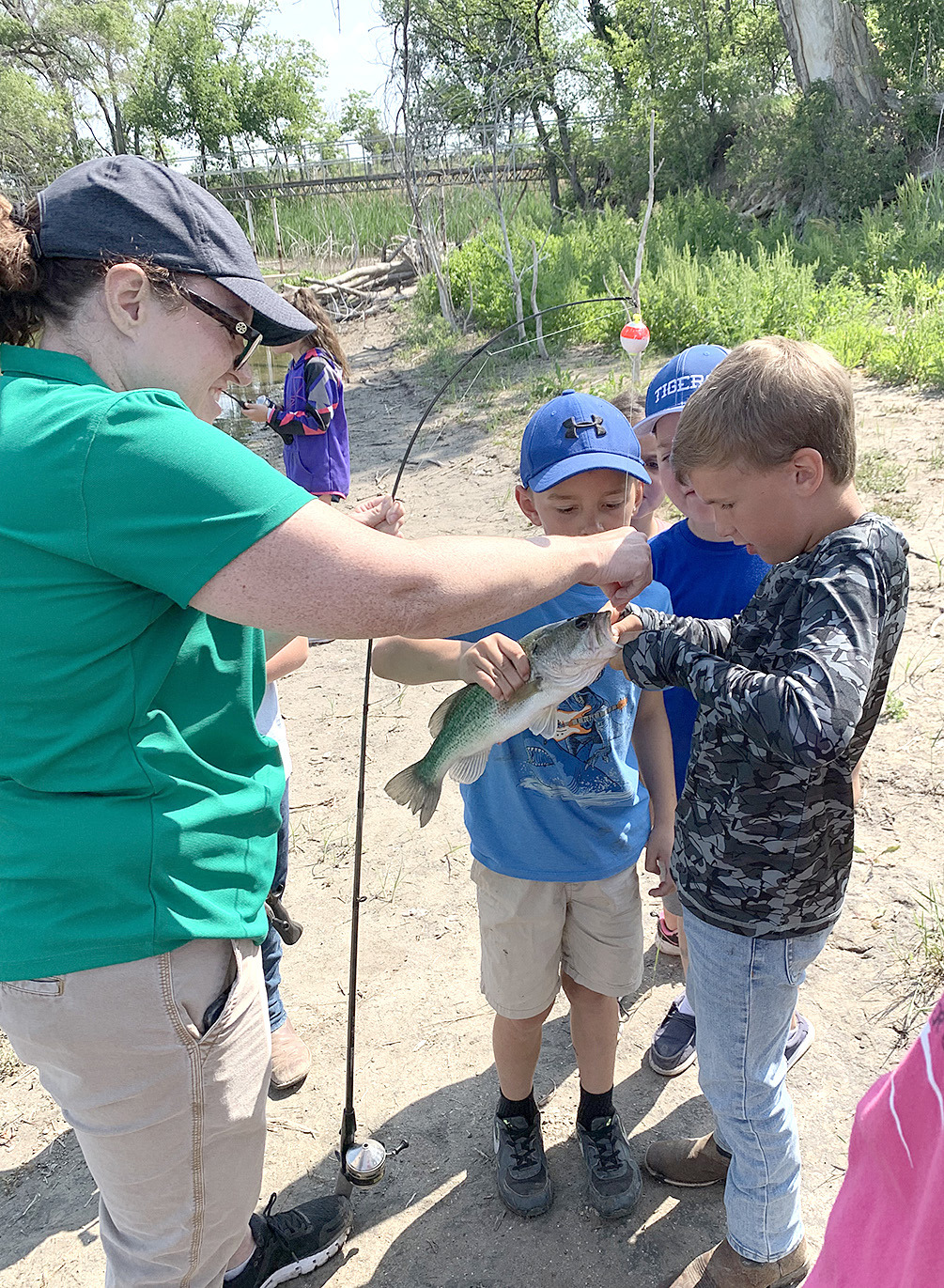 PHILLIPS-ROOKS DISTRICT AGENT CINDYWALKER shows the boys how to unhook a fish during Outdoor Adventure Day.