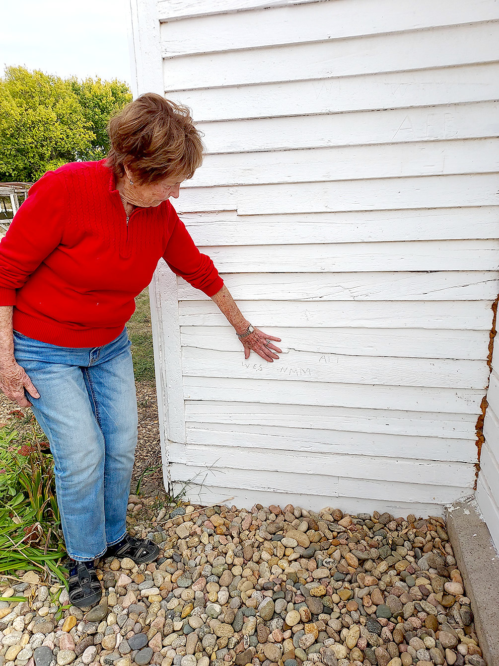 JOAN BALDERSTON shows where her sister, Naomi May, carved her initials into the Prairie View schoolhouse many years ago. The school resides on the Dawn and Jim O’Grady farm south of Stockton.