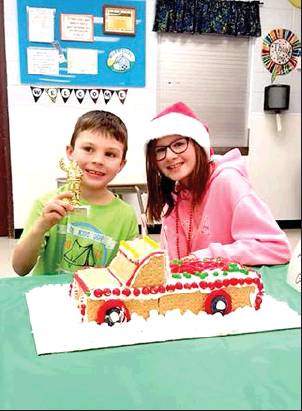 REPRESENTING THE ATKISSON/GASPER TEAM, Eli Atkisson and Meredith Gasper proudly display their "gingerbread" truck creation which won them the "Most Holly Jolly" trophy at the Gingerbread Family Night, sponsored December 5th by the Stockton Rec.