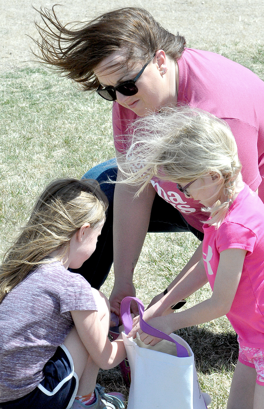 FINLEY PETERSON, CHELSEY PETERSON and Hadlyn Becker look for treasures in their baskets following the Sigma Phi ESA Easter Egg Hunt held on April 15 at the Lower City Park.