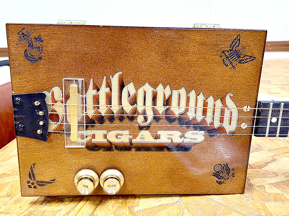 THE GUITAR donated for the upcoming fundraiser for the Stockton VFW and American Legion is made from a “Battleground Cigars” box with the four service insignias lasered into the four corners.