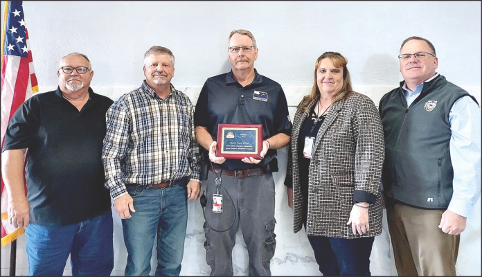 ROOKS COUNTY EMERGENCY MANAGEMENT DIRECTOR BUTCH POST was honored at the October 18th Rooks County Commission meeting with two plaques for his service in the Kansas Emergency Management Association as a member and past president. Pictured are (from left): Rooks County Commissioners Tim Berland and John Ruder, Rooks County Emergency Management Director Butch Post, KEMA President Kathleen Fabrizius and State Emergency Management Regional Coordinator Toby Prine.
