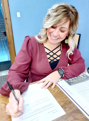 KAYLA HILBRINK signs her name to the official documents after being sworn in on Monday, January 9th by Rooks County Clerk Laura Montgomery as the first woman to be elected to serve on the Rooks County Commission for District #1.