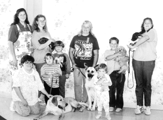 FIRST PLACE WINNERS at the Pet Parade held in the fall of 1991 were (front row, from left) Kelly Schonthaler, Heather Schonthaler, and Asia Schonthaler with their dog, C J; Brittanie Marcotte with her dog Felicia; (back row) Marissa Haines and Richelle Haines with their pot-bellied pig Oscar; Kathy Creighton and her dog Max; Weston Inglsbee and his dog Ginger; and Melanie Haines and her dog Barney.