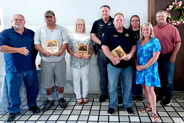 TEN-YEAR ANNIVERSARY PLAQUES for service to the County were presented at the May 30th Rooks County Commission meeting. Pictured are (from left): commissioner Tim Berland, Tracy Grieve, Denise Murchie, sheriff Gary Knight, deputy Colin Hockett, Angel Amlong, and commissioners Kayla Hilbrink and John Ruder.